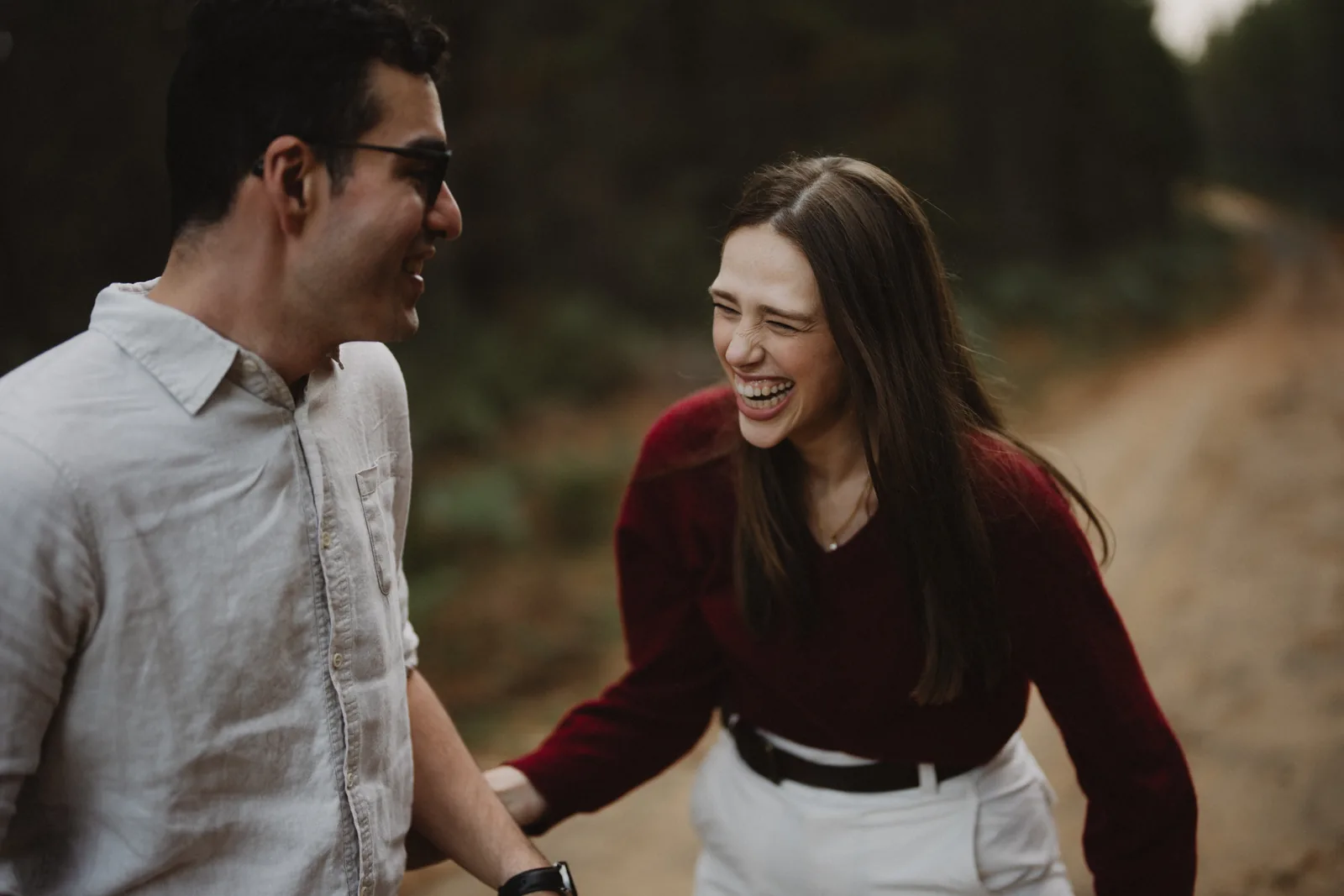 Phoebe and Massimo walking through a pine forest road